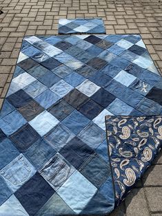 an old blue patchwork quilt laying on the ground with it's end torn off