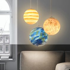 three different types of lights hanging from the ceiling in a living room, one with an orange and blue planet on it