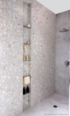 a bathroom with a walk in shower next to a white tiled wall