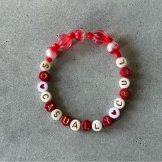 a red and white beaded bracelet with the word love spelled in letters on it