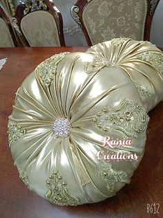 two decorative pillows sitting on top of a wooden dining room table with chairs in the background