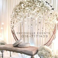 a bed with pillows and flowers on it in front of a white curtained backdrop