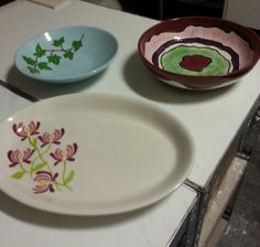 two bowls with designs on them sitting on a counter top next to another bowl that has flowers painted on it