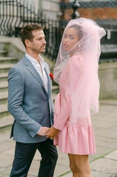 a man and woman standing next to each other in front of stairs wearing veils