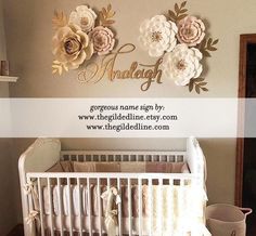 a white crib with some flowers on the wall and a name sign above it