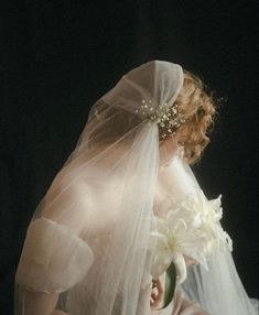 a woman wearing a veil holding a bouquet of flowers