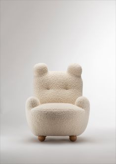 a chair made out of sheep's wool with wooden legs and feet, sitting in front of a white background