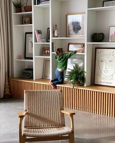 a young child climbing up the side of a book shelf in a living room with bookshelves