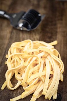 a pile of pasta sitting on top of a wooden table next to a spatula