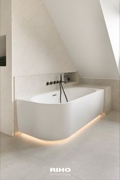 a white bathtub sitting under a slanted ceiling next to a wall mounted faucet