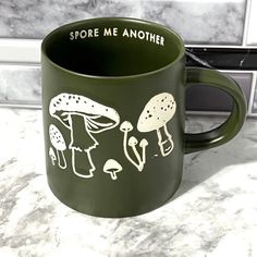 a green coffee mug with mushrooms on it and the words store me another written in white