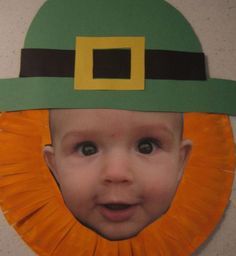 a child wearing a green hat and orange ribbon around his head with a yellow square in the center