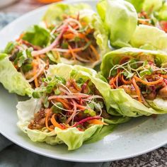 lettuce wraps filled with meat and veggies on top of a white plate