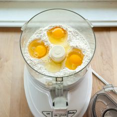 an electric blender with four eggs in it