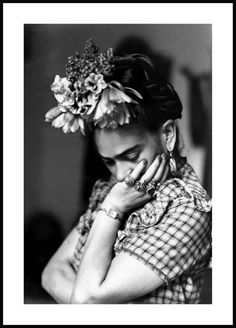 a black and white photo of a woman with flowers in her hair, holding her hands to her face