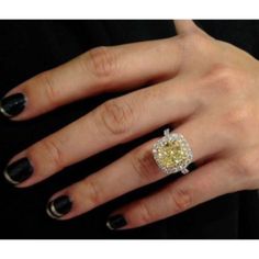 a woman's hand with a yellow diamond ring on it