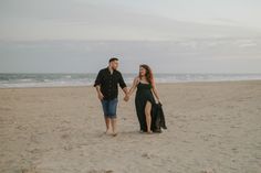 a man and woman walking on the beach holding hands