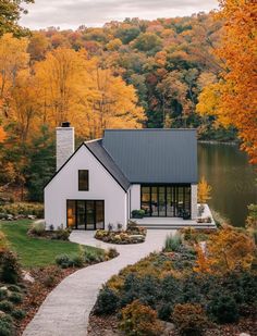 a white house surrounded by trees with fall foliage in the foreground and a path leading to it