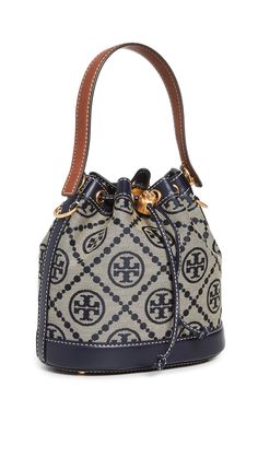 PRICES MAY VARY. Fabric: Jacquard Structured silhouette, Gold-tone hardware, Monogram print Length: 8.25in / 21cm, Height: 8.25in / 21cm, Handle drop: 4in / 10cm, Strap drop: 21.75in / 55cm, Depth: 4.75in / 12cm Drawstring closure Patch interior pocket A scaled-down Tory Burch bucket bag, detailed with a rendition of the label's monogram for a polished and eye-catching look. Two shades of leather trim lend an eclectic finish to the silhouette. Tory Burch Bucket Bag, T Monogram, Mini Bucket Bags, Mini Bucket, Monogram Prints, Tory Burch Miller, Tory Burch Bag, Metallic Logo, Free Bag