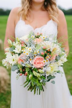 a woman in a white dress holding a bridal bouquet with pink and yellow flowers