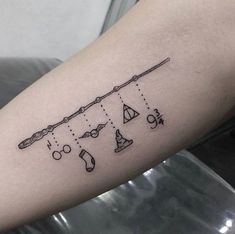 a tattoo on the arm of a woman with an arrow and other items hanging from it