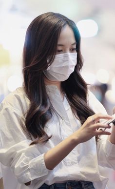 a woman wearing a face mask while looking at her cell phone