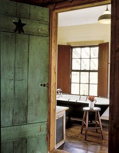 an open door leading to a bathroom with a bathtub and stool in the corner