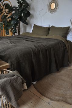 a bed sitting on top of a wooden floor next to a plant