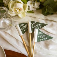 three green and white flags sitting on top of a wooden table next to some flowers