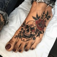 a woman's foot with a skull and roses tattoo on it