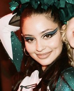 a woman with green and black makeup posing for the camera