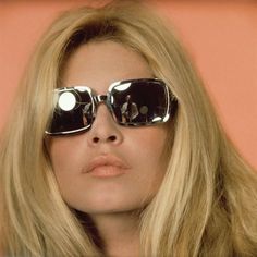 a blonde woman wearing sunglasses and looking at the camera with her eyes wide open in front of her face