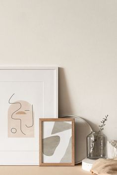 an art print is displayed on a shelf next to a vase with flowers in it