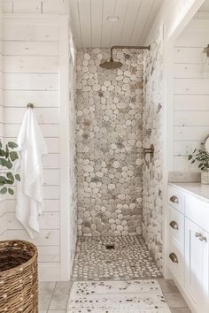 a white bathroom with a stone shower and rug on the floor in front of it