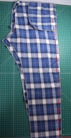 the blue and white checkered shirt is laying on top of green cutting mat with scissors