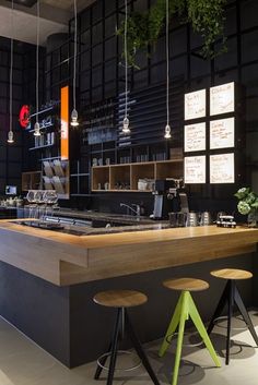 an empty restaurant bar with stools and lights hanging from the ceiling, along with menu boards on the wall