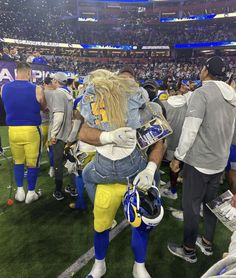 a football player is hugging another person on the sidelines at a game with other players