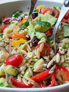 a close up of a salad in a bowl with two tongs sticking out of it