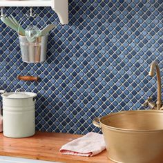 a kitchen with blue and white tiles on the wall, wooden counter top and sink