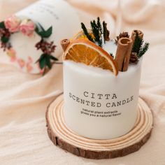 an orange slice and cinnamon sticks are in a white candle holder on a wooden coaster