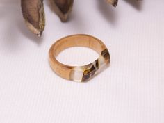 a wooden ring sitting on top of a white table next to dried flowers and leaves