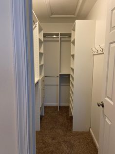 an empty walk in closet with white walls and carpeted flooring is seen from the doorway