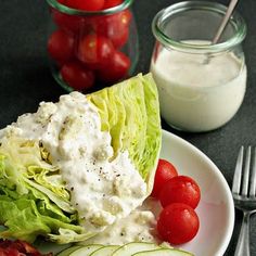 lettuce, tomato and cucumber with ranch dressing on a white plate