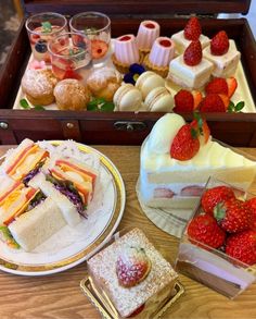 there are many different desserts on the table and in the box, including strawberries