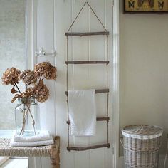 a towel rack hanging on the wall next to a basket with dried flowers in it