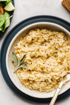 a bowl of macaroni and cheese on a plate with a spoon next to it