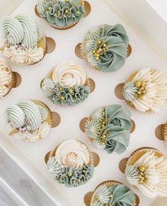 twelve cupcakes with green and white frosting in a box on a table