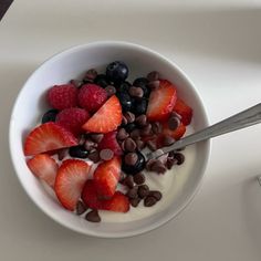 a white bowl filled with berries and chocolate chips