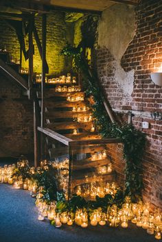 candles are lined up on the stairs in front of an old brick wall and staircase