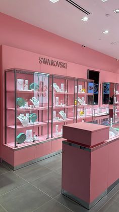 a store with pink walls and shelves filled with different types of items on display in glass cases